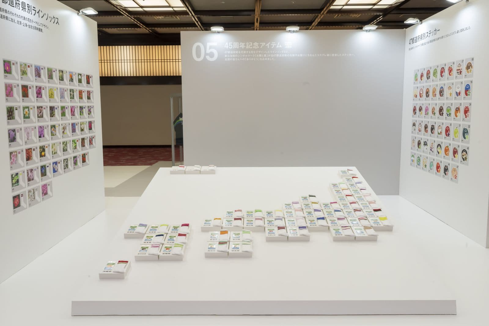 Dozens of white sock packs laid out on a white plinth in the shape of the Japanese archipelago, with sock and sticker lineup boards on the walls behind