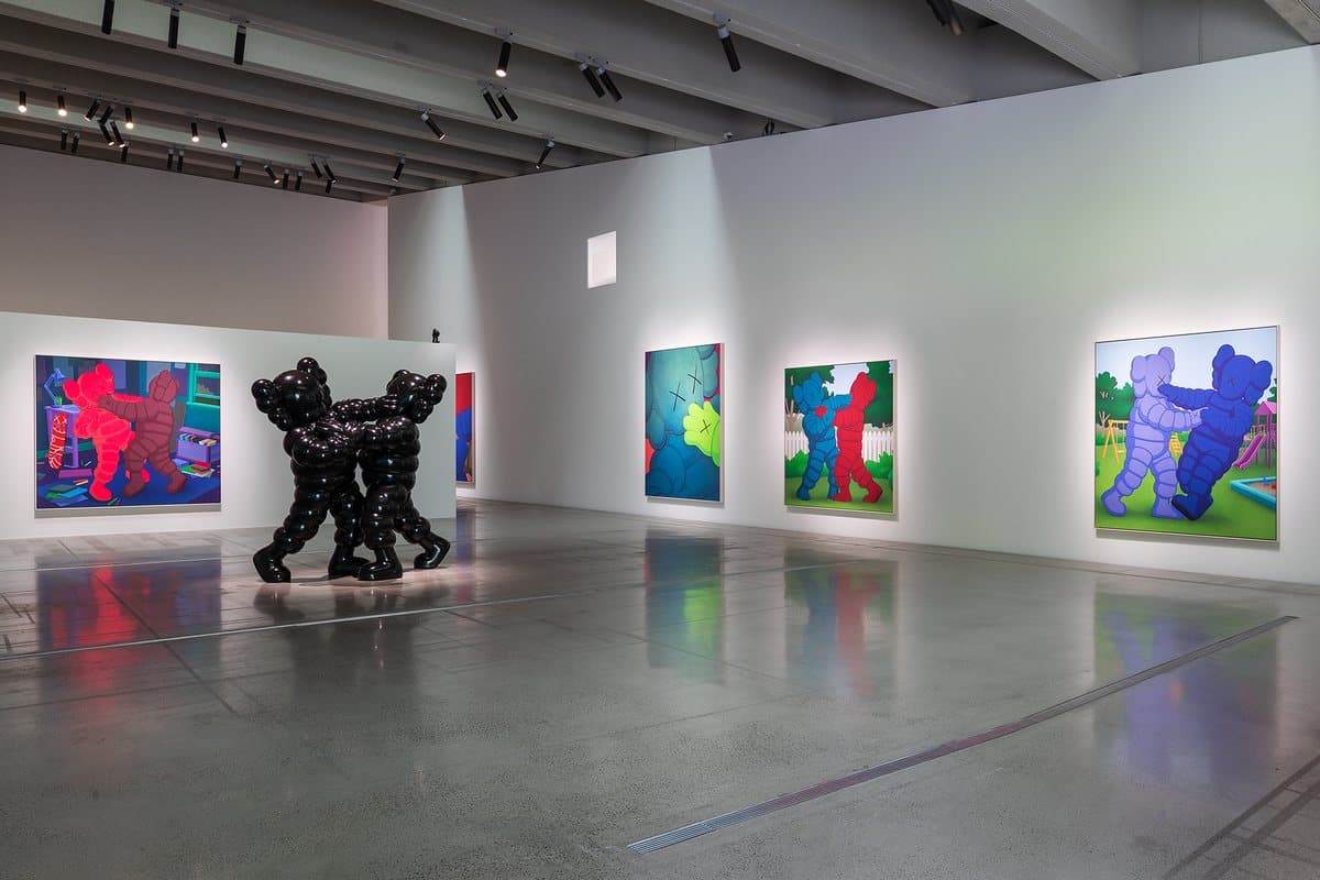 A gallery at Space K Seoul with a black KAWS sculpture and colourful paintings