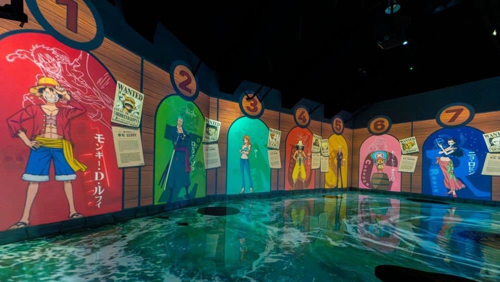 A shallow pool running past a wall of One Piece wanted posters at Water World Jeju
